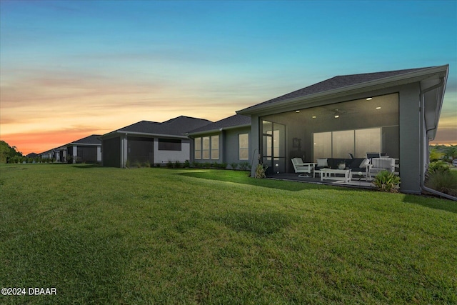 back house at dusk featuring an outdoor living space and a yard