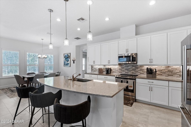 kitchen with hanging light fixtures, an island with sink, appliances with stainless steel finishes, and sink