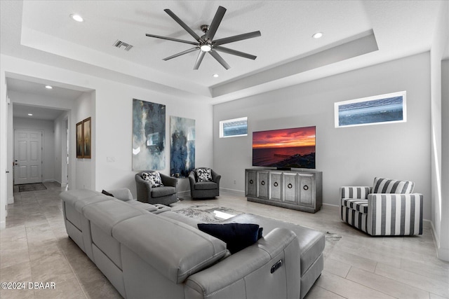 living room featuring ceiling fan and a raised ceiling