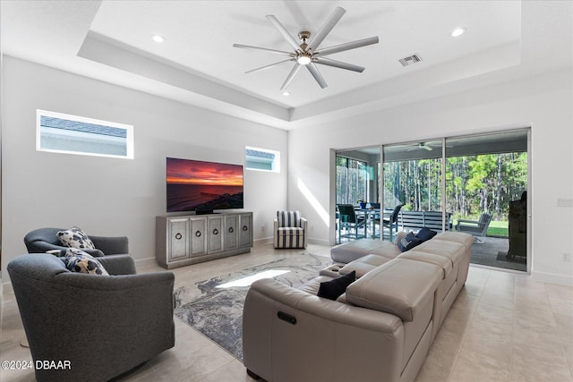 living room featuring ceiling fan and a raised ceiling