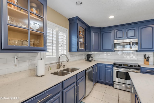 kitchen featuring blue cabinets, sink, light tile patterned floors, tasteful backsplash, and stainless steel appliances