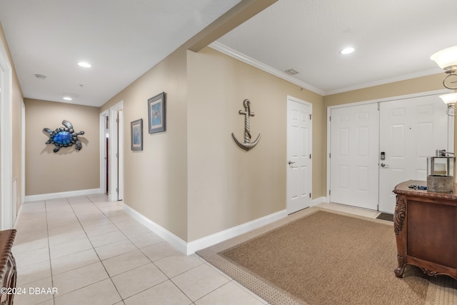 foyer with light tile patterned flooring and crown molding