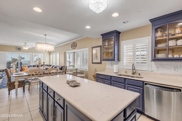 kitchen featuring backsplash, ceiling fan with notable chandelier, sink, stainless steel dishwasher, and decorative light fixtures