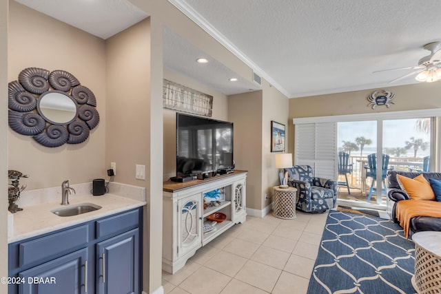 tiled living room featuring ceiling fan, sink, crown molding, and a textured ceiling