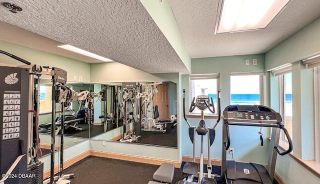 exercise room with a water view and a textured ceiling