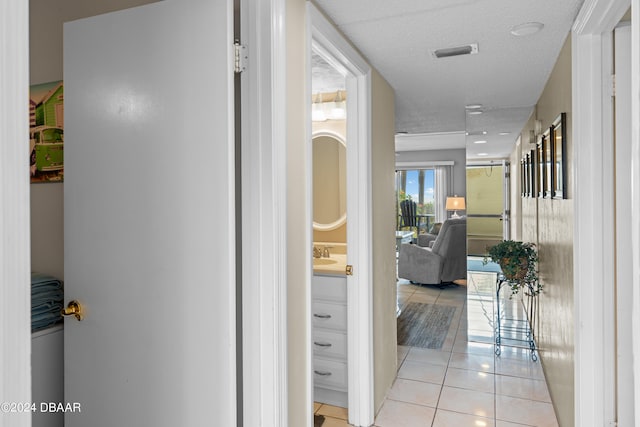 hallway with a textured ceiling, light tile patterned floors, and sink