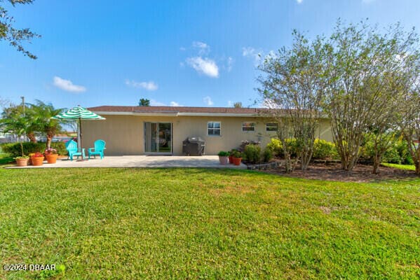 rear view of house featuring a lawn and a patio