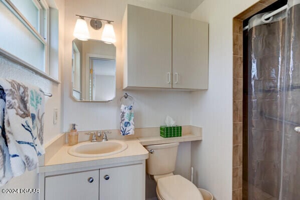 bathroom featuring a tile shower, vanity, and toilet