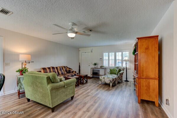 living room with hardwood / wood-style floors, ceiling fan, and a textured ceiling