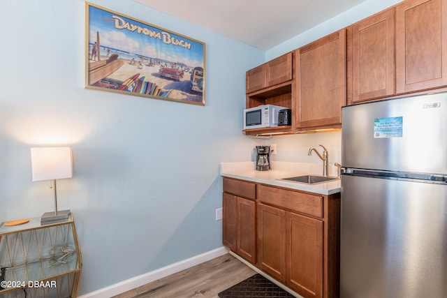 kitchen with sink, stainless steel refrigerator, and light hardwood / wood-style flooring