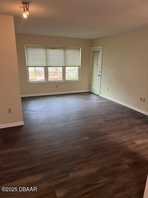 empty room featuring a textured ceiling and dark wood-type flooring