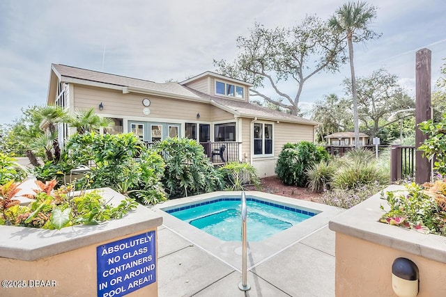 rear view of property featuring an in ground hot tub