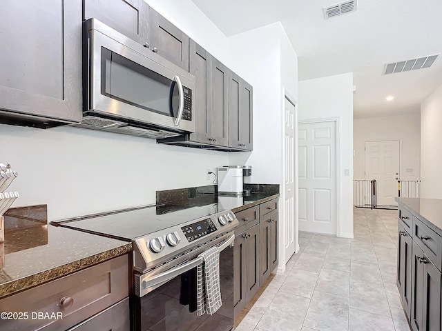 kitchen featuring dark stone countertops, light tile patterned floors, and stainless steel appliances