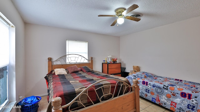 bedroom with ceiling fan, a textured ceiling, and light tile patterned floors