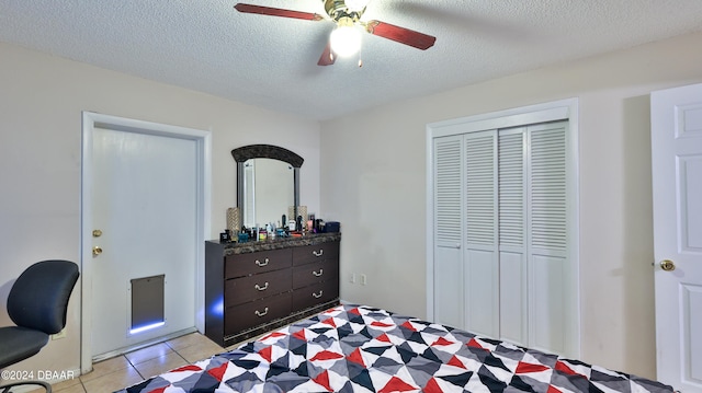 tiled bedroom with a textured ceiling, ceiling fan, and a closet