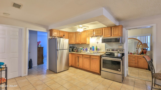 kitchen featuring stainless steel appliances, decorative backsplash, a textured ceiling, ceiling fan, and light tile patterned flooring