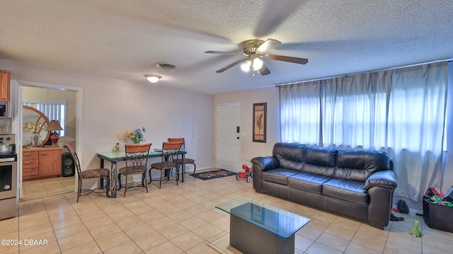 living room featuring a textured ceiling, ceiling fan, and light tile patterned floors