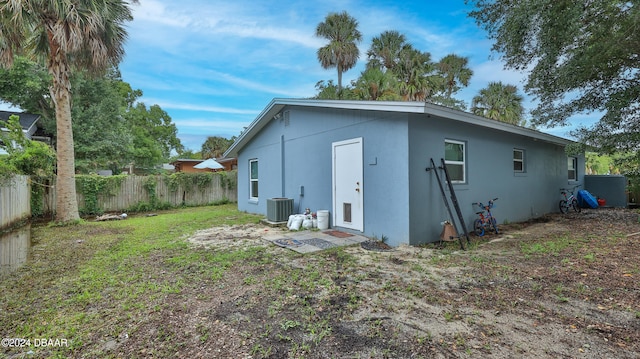 rear view of property with central AC unit and a yard