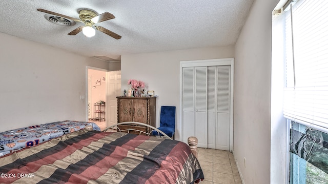 tiled bedroom featuring a textured ceiling, ceiling fan, and a closet