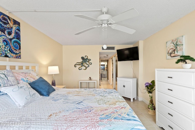 bedroom featuring light tile patterned floors, visible vents, a textured ceiling, and a ceiling fan