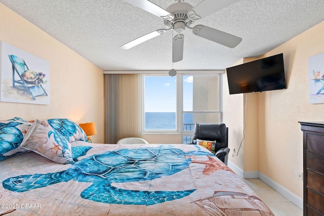 bedroom featuring light tile patterned floors, baseboards, a ceiling fan, and a textured ceiling