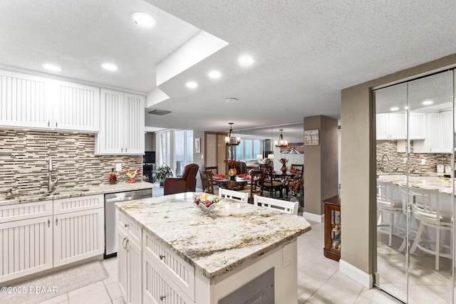 kitchen featuring a chandelier, white cabinetry, a kitchen island, and stainless steel dishwasher