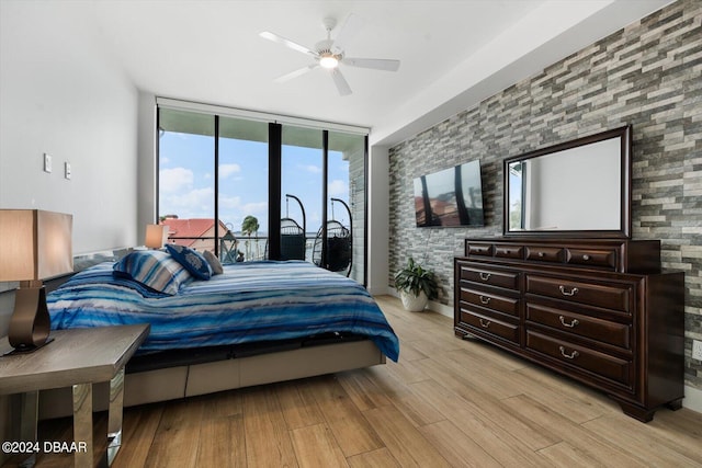 bedroom featuring ceiling fan, a wall of windows, and light hardwood / wood-style floors