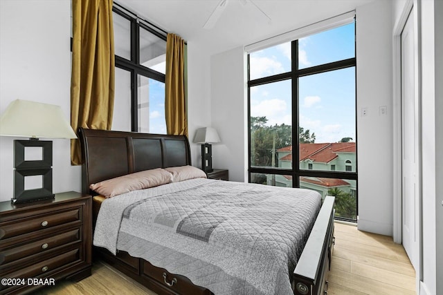 bedroom featuring ceiling fan, a wall of windows, and light wood-type flooring