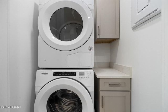 laundry room featuring cabinets and stacked washer and clothes dryer