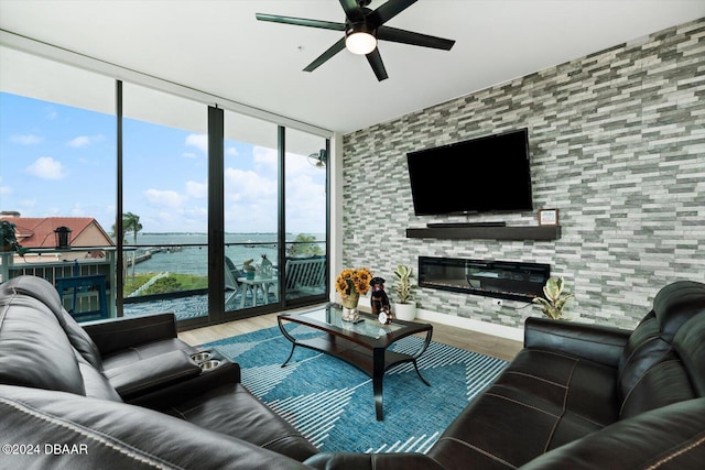 living room featuring ceiling fan, a large fireplace, hardwood / wood-style floors, and expansive windows