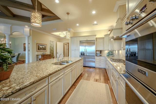 kitchen featuring appliances with stainless steel finishes, decorative light fixtures, a sink, and ornate columns