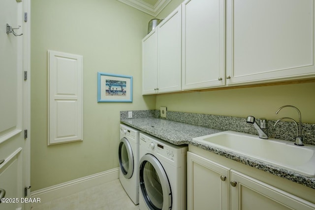 laundry area with crown molding, cabinet space, washing machine and dryer, a sink, and baseboards