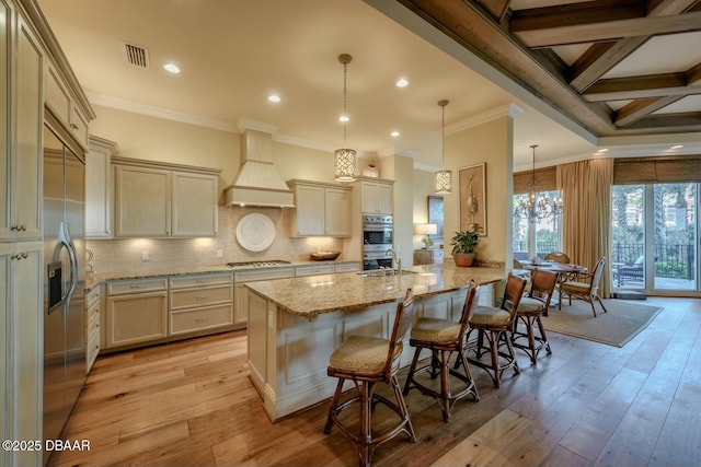 kitchen featuring a peninsula, premium range hood, visible vents, appliances with stainless steel finishes, and a kitchen bar