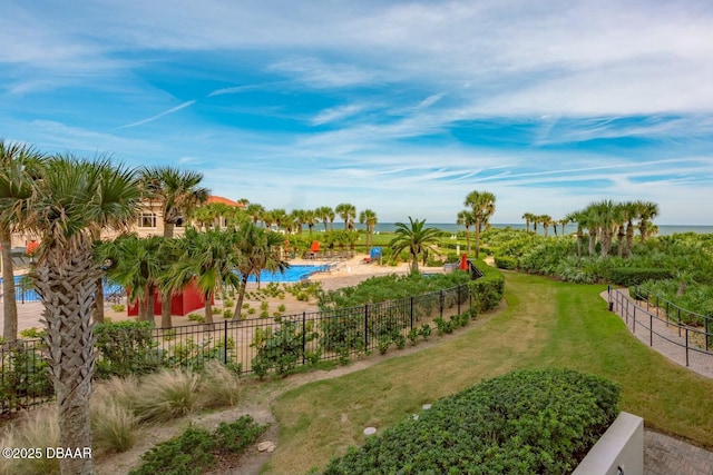 exterior space featuring a lawn, a water view, fence, and a pool