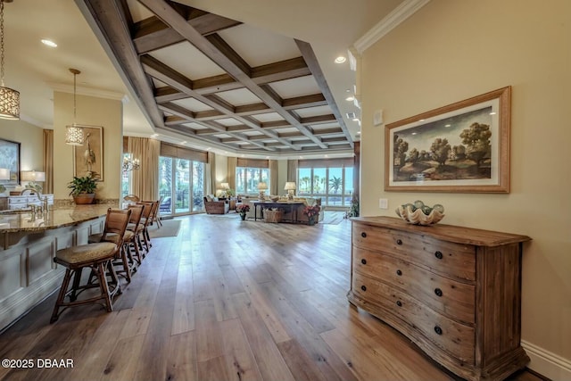 interior space with ornamental molding, coffered ceiling, wood finished floors, and beam ceiling