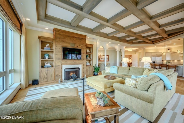 living area with arched walkways, beam ceiling, a fireplace, light wood finished floors, and coffered ceiling