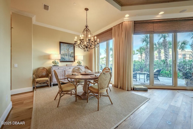 dining space featuring visible vents, an inviting chandelier, ornamental molding, light wood-style floors, and baseboards