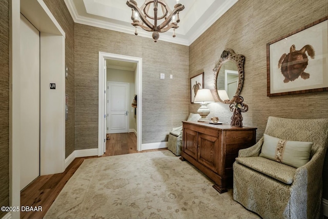 living area with a notable chandelier, baseboards, elevator, light wood finished floors, and crown molding