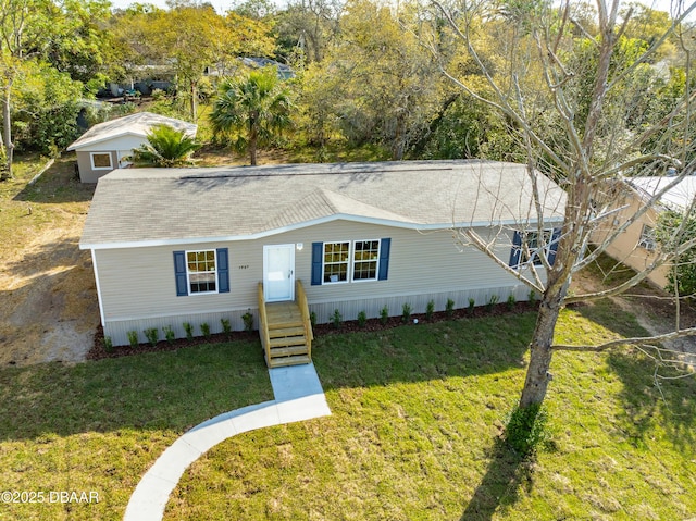 manufactured / mobile home featuring a front lawn and roof with shingles