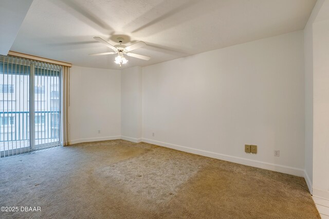 carpeted spare room featuring a ceiling fan and baseboards