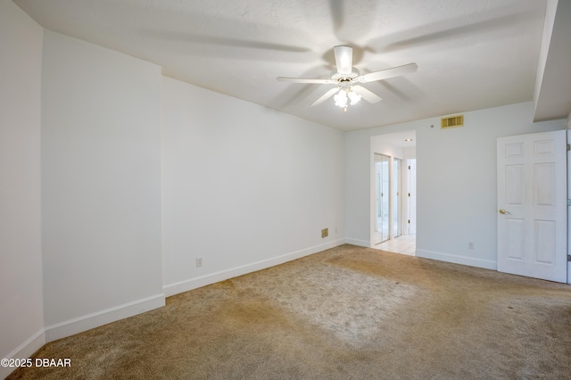 spare room featuring light carpet, ceiling fan, visible vents, and baseboards