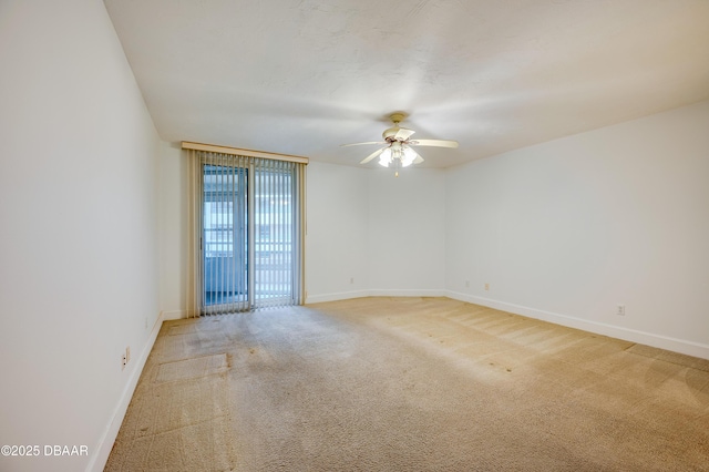 carpeted empty room featuring a ceiling fan and baseboards