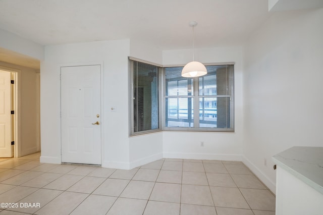 unfurnished dining area with baseboards and light tile patterned floors