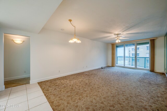 empty room with light tile patterned floors, light colored carpet, a ceiling fan, and baseboards