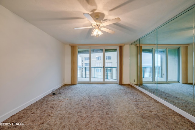 spare room featuring carpet, expansive windows, baseboards, and ceiling fan