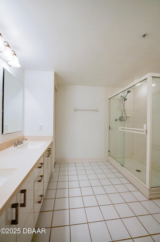 bathroom with double vanity, a sink, a shower stall, and tile patterned floors