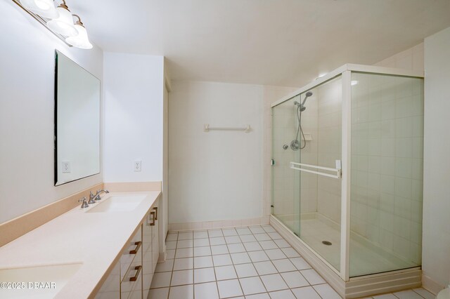 full bathroom with double vanity, a stall shower, baseboards, tile patterned floors, and a sink