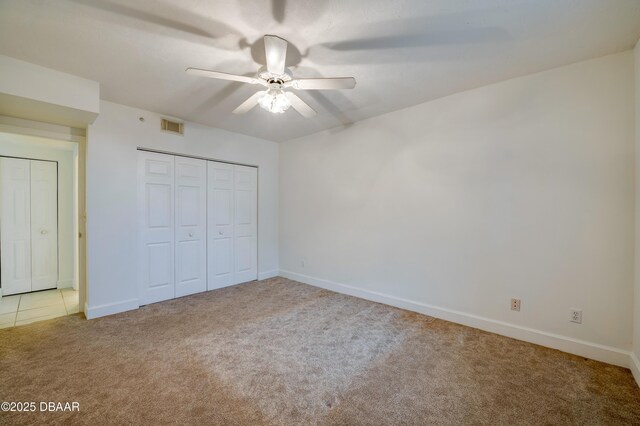 unfurnished bedroom featuring a closet, carpet flooring, visible vents, and baseboards