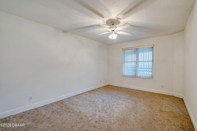 carpeted spare room with a ceiling fan and baseboards