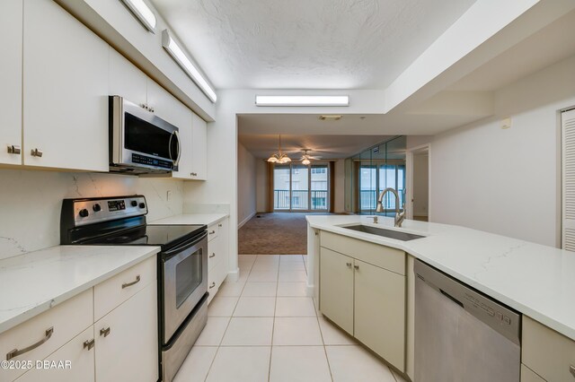 kitchen with decorative light fixtures, light tile patterned floors, stainless steel appliances, a sink, and a textured ceiling